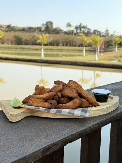 Isca de peixe na tábua com limão e molho, servida à beira do tanque