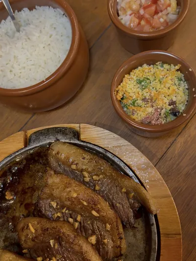 Panceta na tábua com arroz, vinagrete e farofa em cumbucas de barro