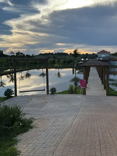 Caminho de pedra até o píer no fim da tarde, com nuvens refletidas no tanque