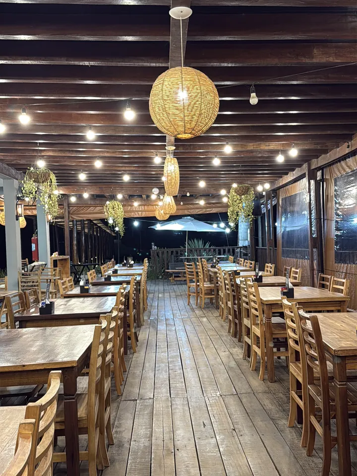 Salão do Pesqueiro Bueno à noite, com varal de luzes e mesas de madeira