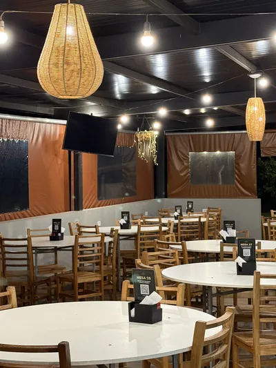 Salão com mesas redondas e luminárias de palha